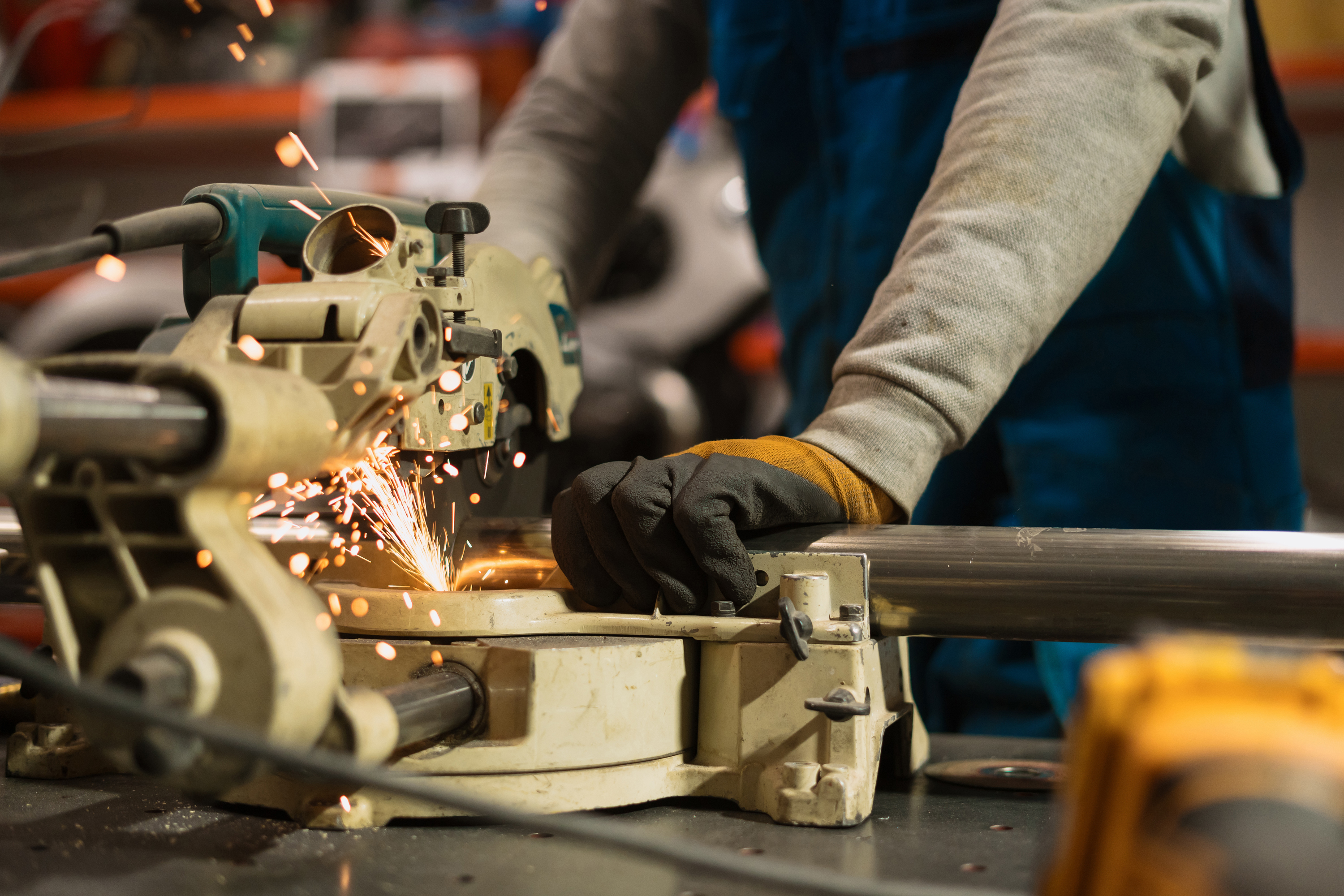 un ouvrier utilise une machine industrielle qui renvoie des étincelles