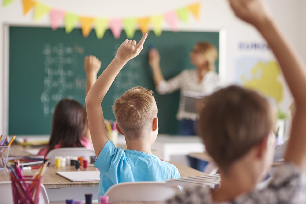 Des élèves en classe lèvent la main pour participer
