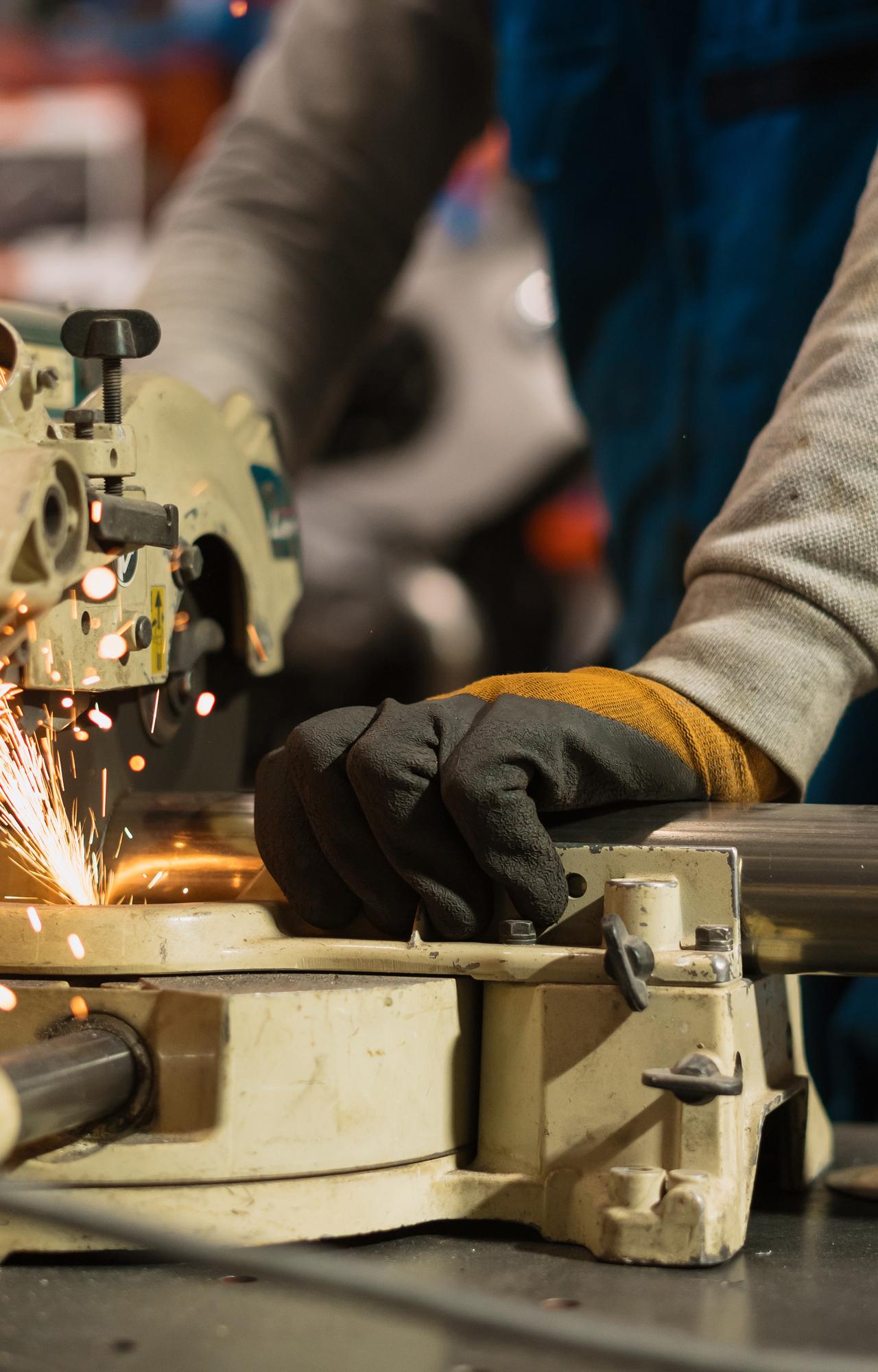 un ouvrier utilise une machine industrielle qui renvoie des étincelles